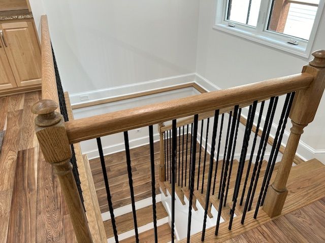 A wooden staircase with a black railing in a house.