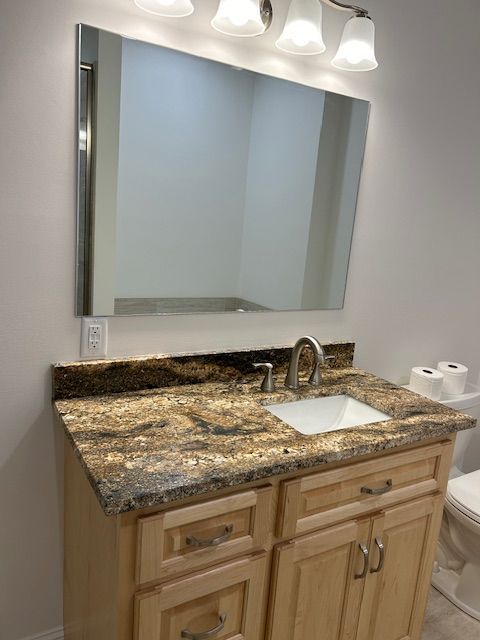 A bathroom with a sink , mirror and toilet.