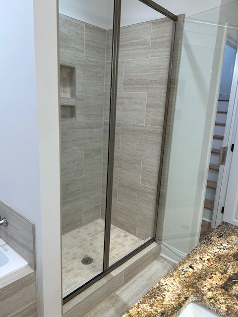 A bathroom with a walk in shower and a sink.