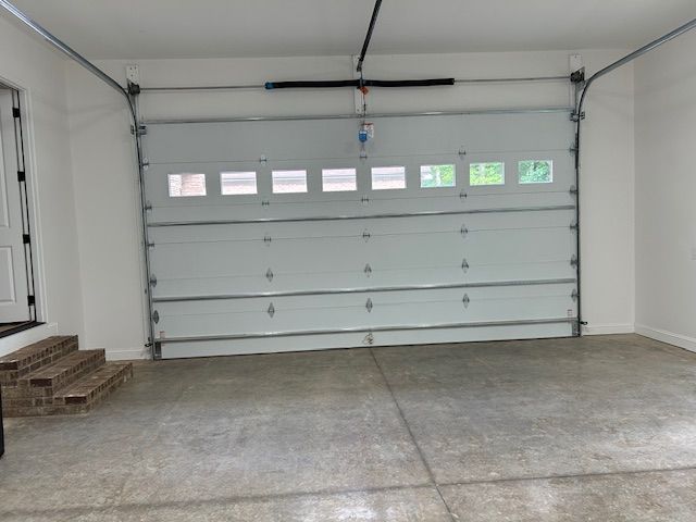 An empty garage with a white garage door and stairs.