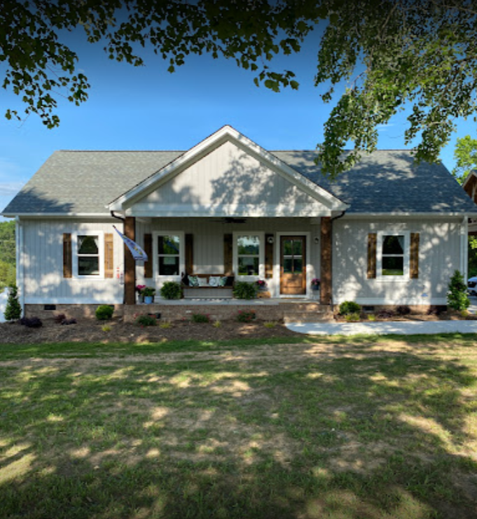 A white house with a gray roof and shutters