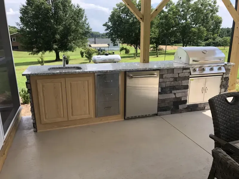 A large outdoor kitchen with a grill , sink , and dishwasher.