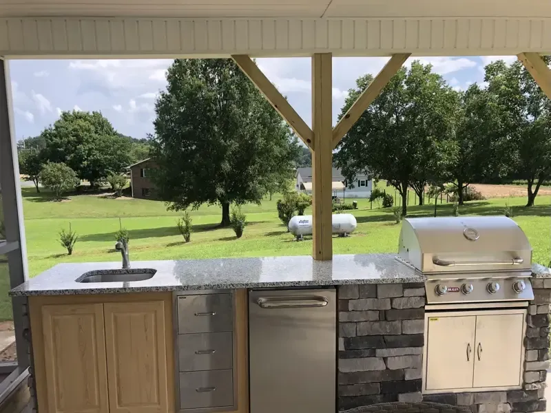 An outdoor kitchen with a grill , sink and dishwasher