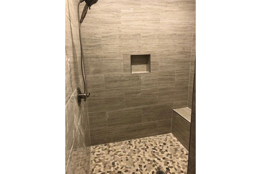 A walk in shower with a tiled floor and a shower head.