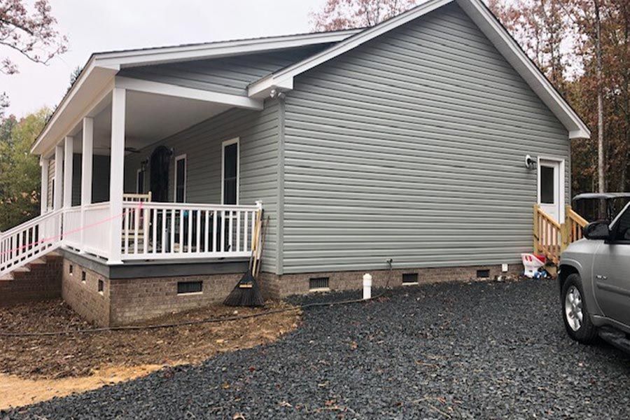 A house with a porch and a car parked in front of it.