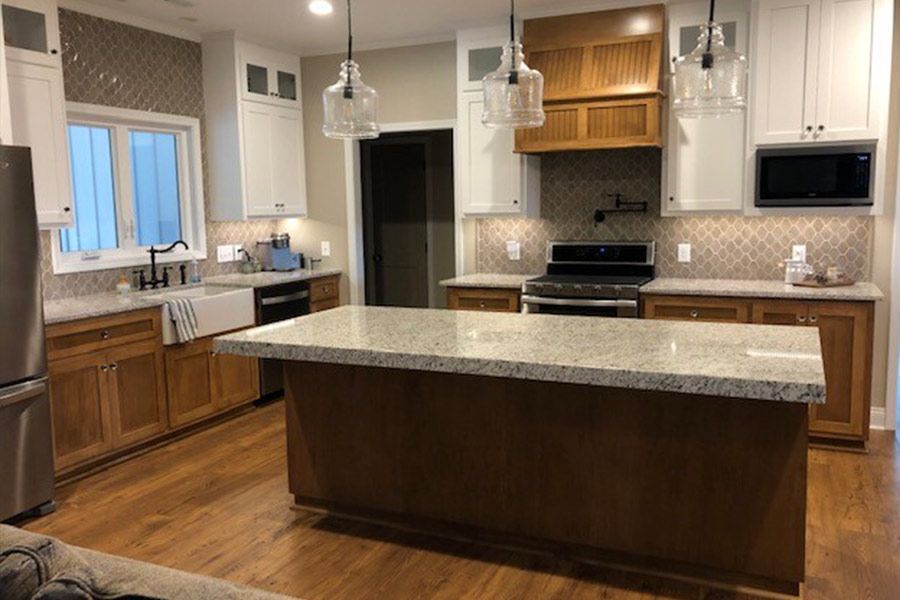A kitchen with wooden cabinets , granite counter tops , stainless steel appliances and a large island.