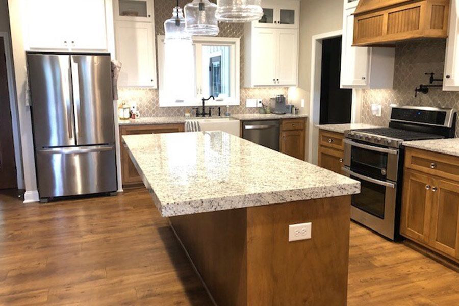 A kitchen with stainless steel appliances and a large island in the middle.