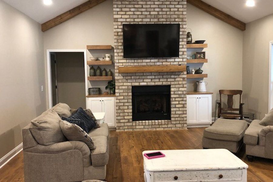 A living room with a brick fireplace and a flat screen tv.