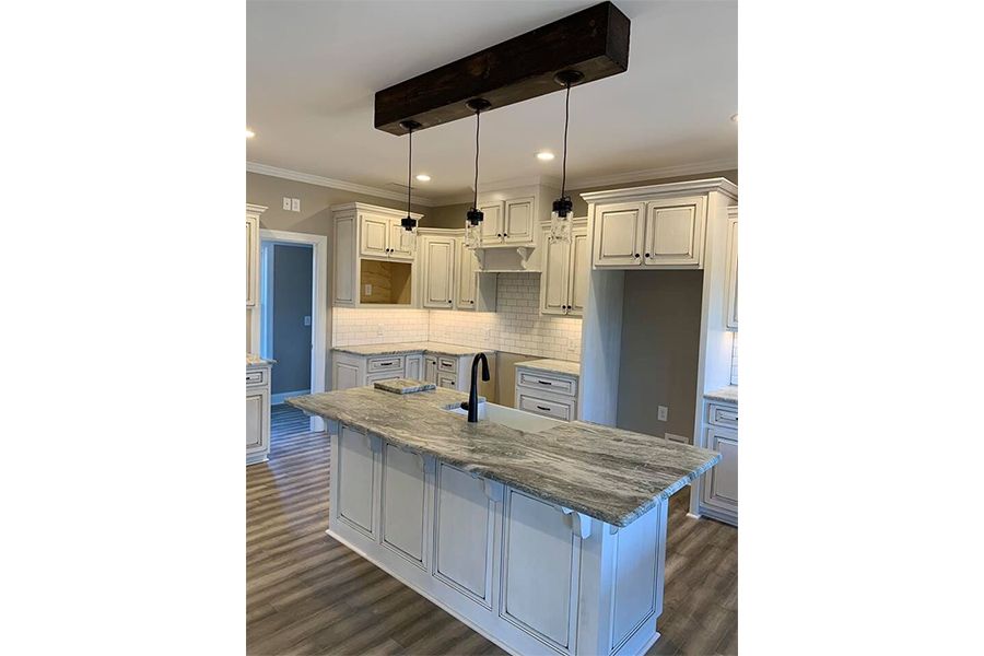 A kitchen with white cabinets , granite counter tops , and a large island.