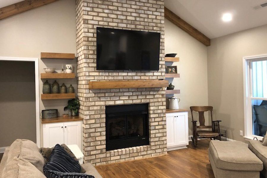 A living room with a brick fireplace and a flat screen tv.