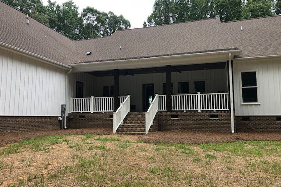 The back of a house with a large porch and stairs leading to it.