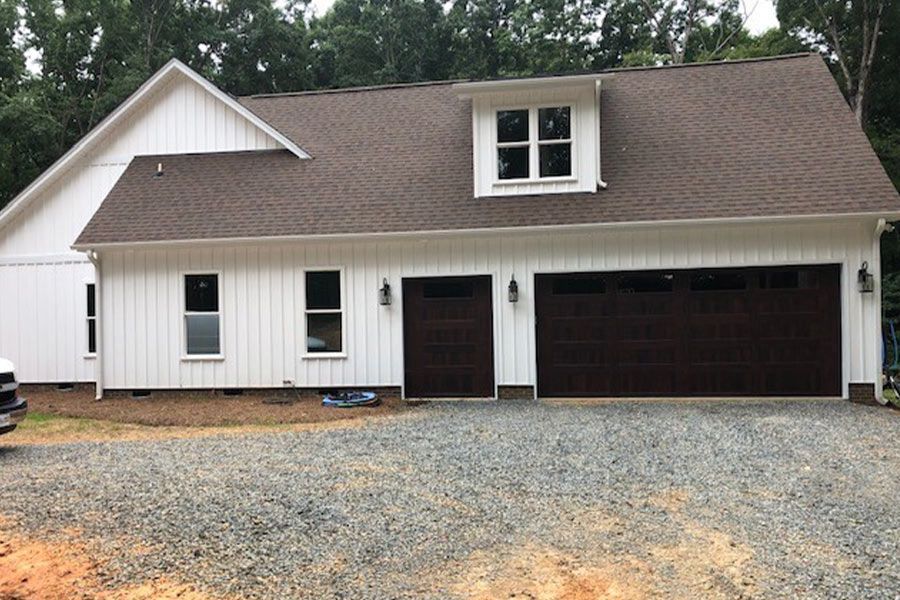 A white house with brown garage doors and a brown roof