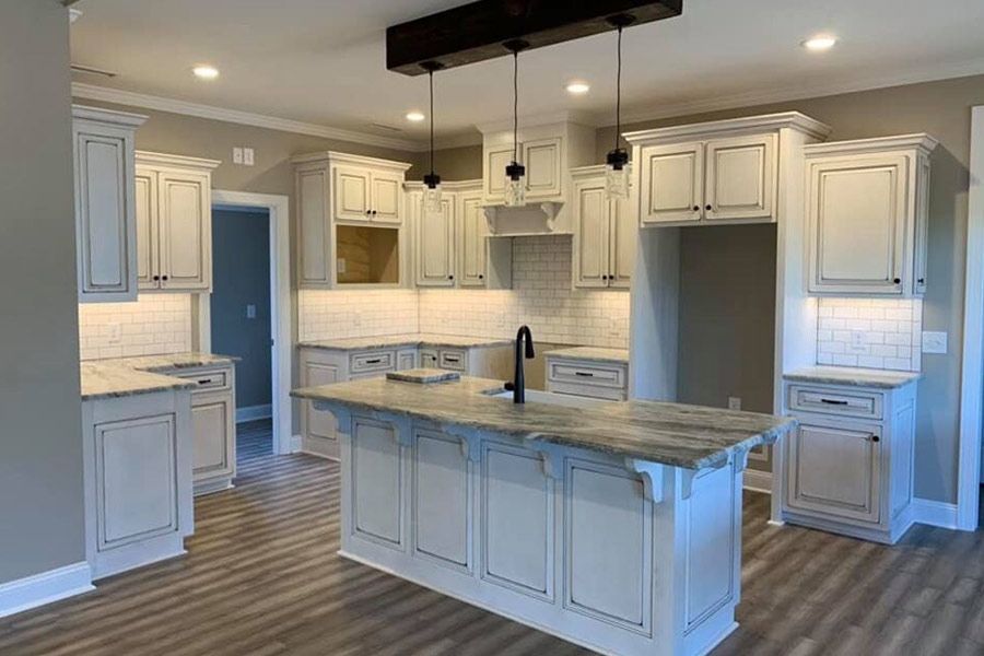 A kitchen with white cabinets , granite counter tops , and a large island.