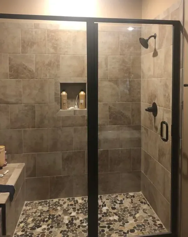 A bathroom with a walk in shower with a glass door.