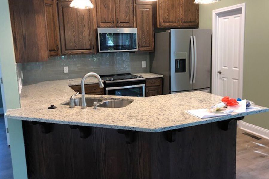 A kitchen with granite counter tops , stainless steel appliances , and wooden cabinets.