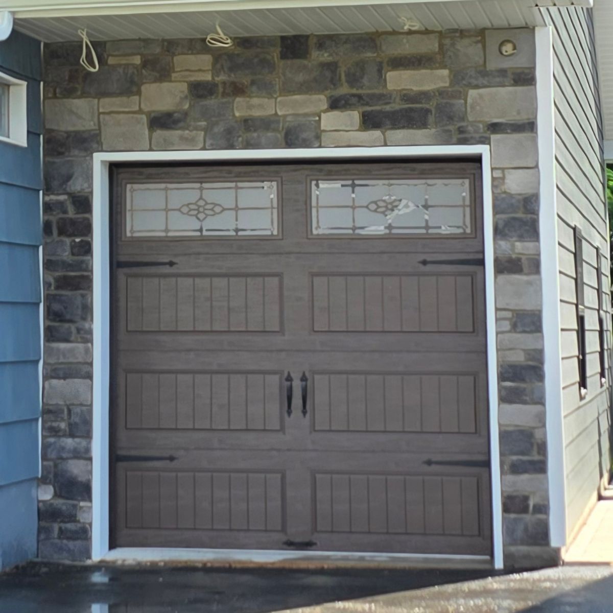 A brown garage door with a stained glass window
