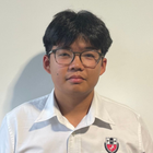 A young man wearing glasses and a white shirt is smiling.