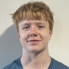 Young man with reddish-blond hair, blue shirt, and a slight smile against a white background.
