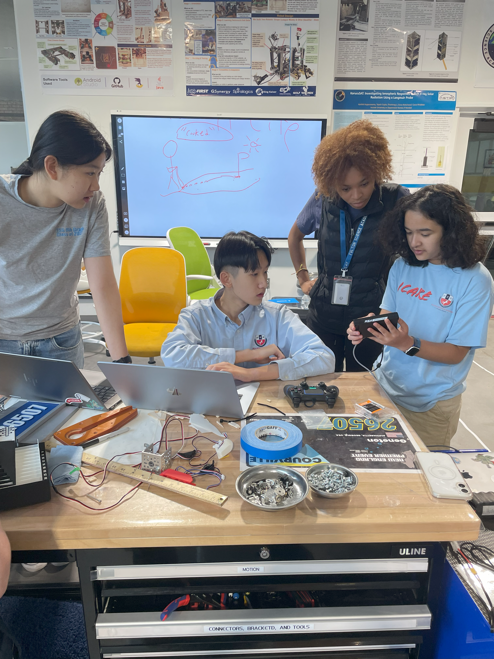 Two young men are working on a robot at a table.