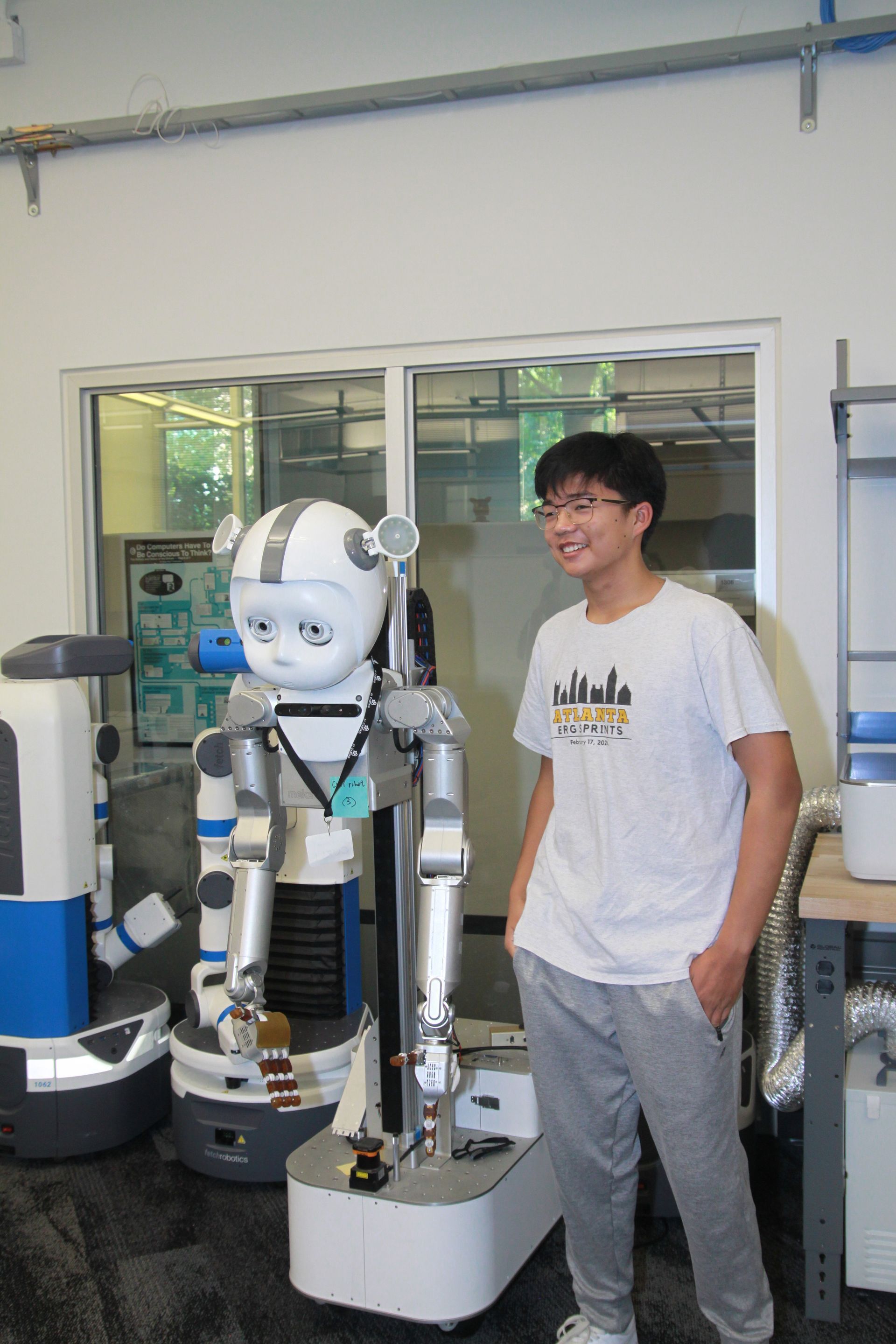 A man in a white shirt is standing next to a robot