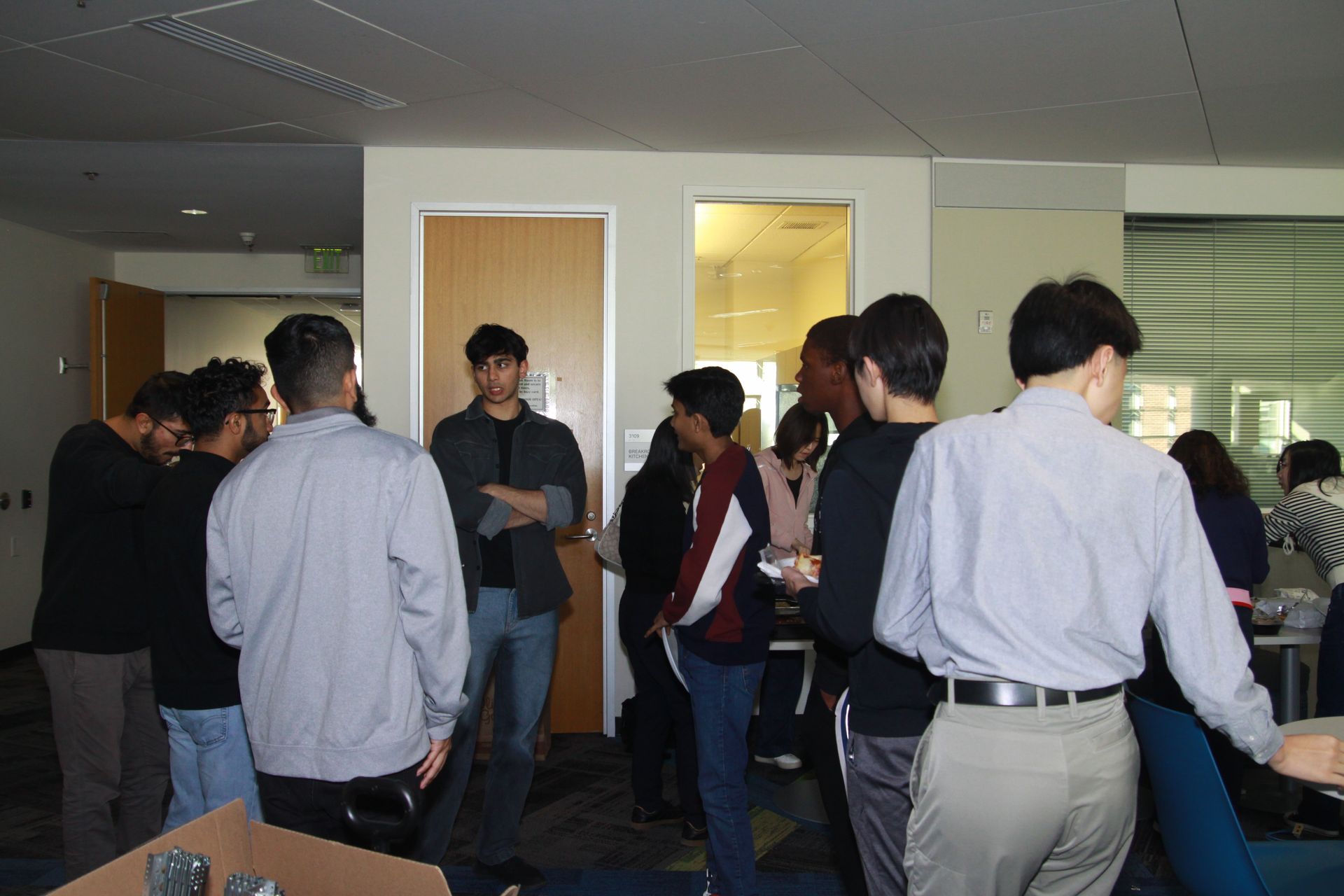 A group of people are standing in a room talking to each other