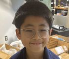 A young boy wearing glasses is smiling for the camera