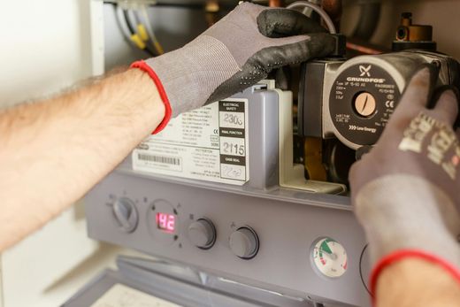 Hands in work gloves servicing a boiler.