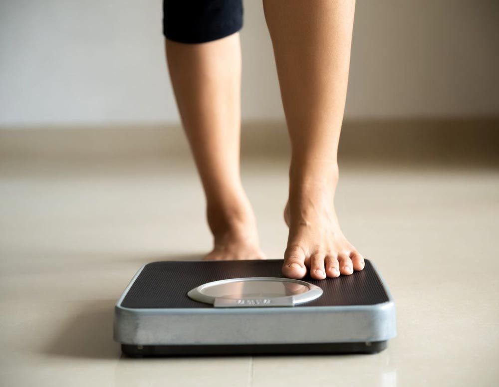 A woman is standing on a scale. - weight loss