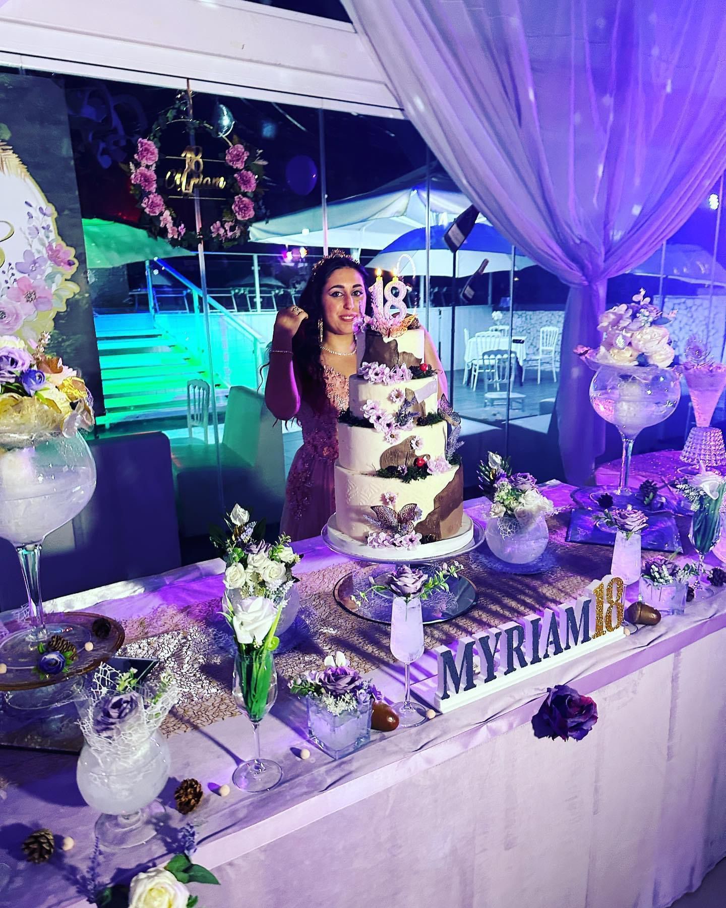 Una donna è in piedi davanti a un tavolo con una torta sopra.