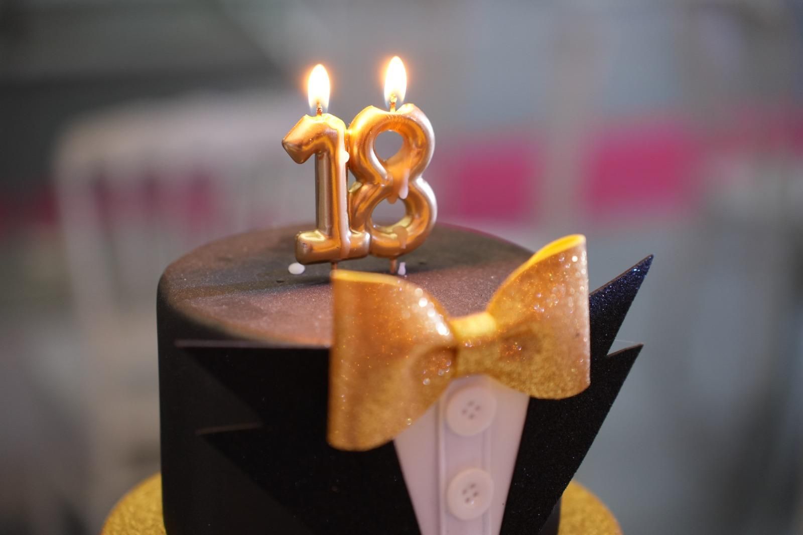 Una torta di compleanno con due candeline a forma di numero 18.