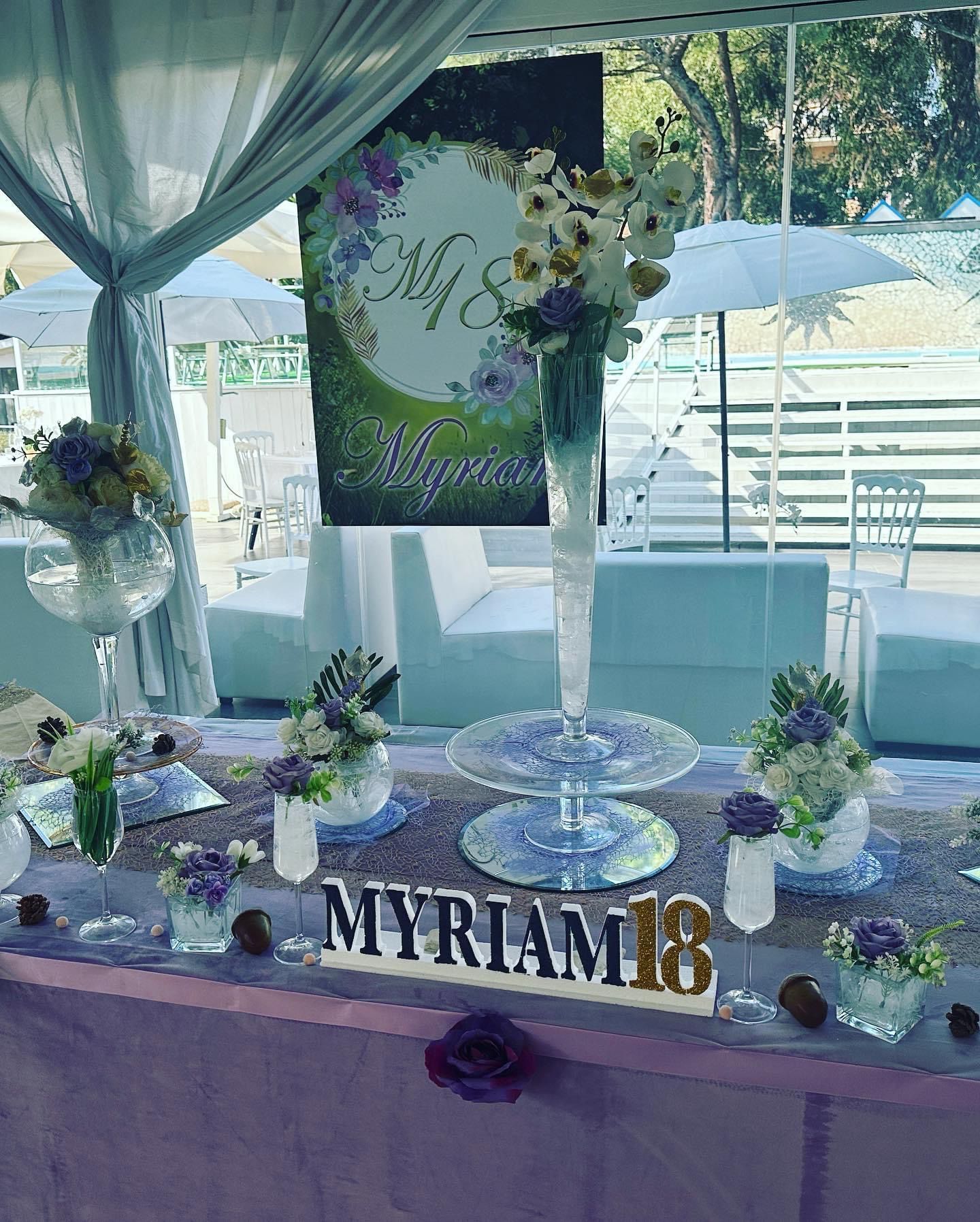 Un tavolo con dei fiori e un cartello con scritto Myriam 18.