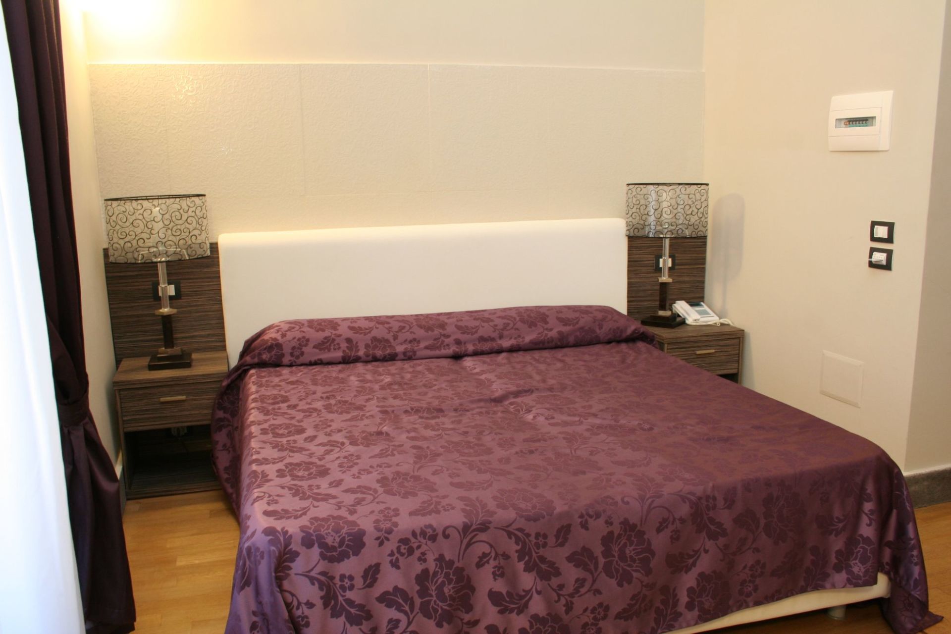 Un letto con un piumone viola in una stanza d'albergo