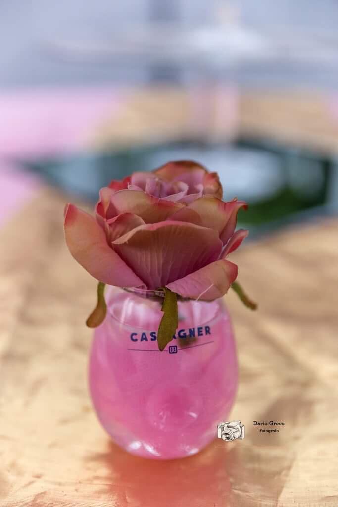 Una rosa rosa è in un bicchiere rosa su un tavolo.