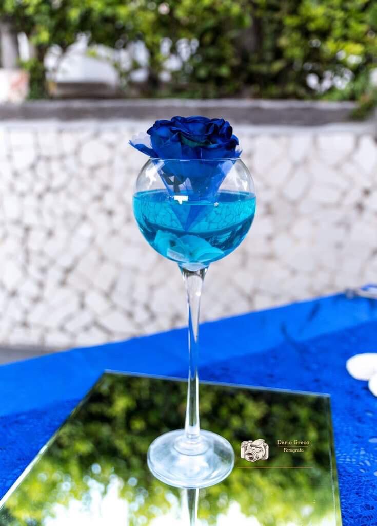 Una rosa blu è in un calice da vino su un tavolo.