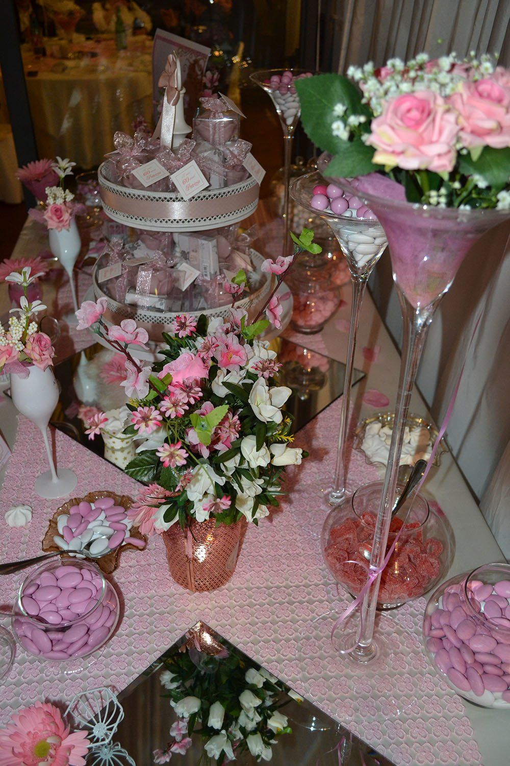 Un tavolo decorato con fiori rosa, caramelle e una torta.