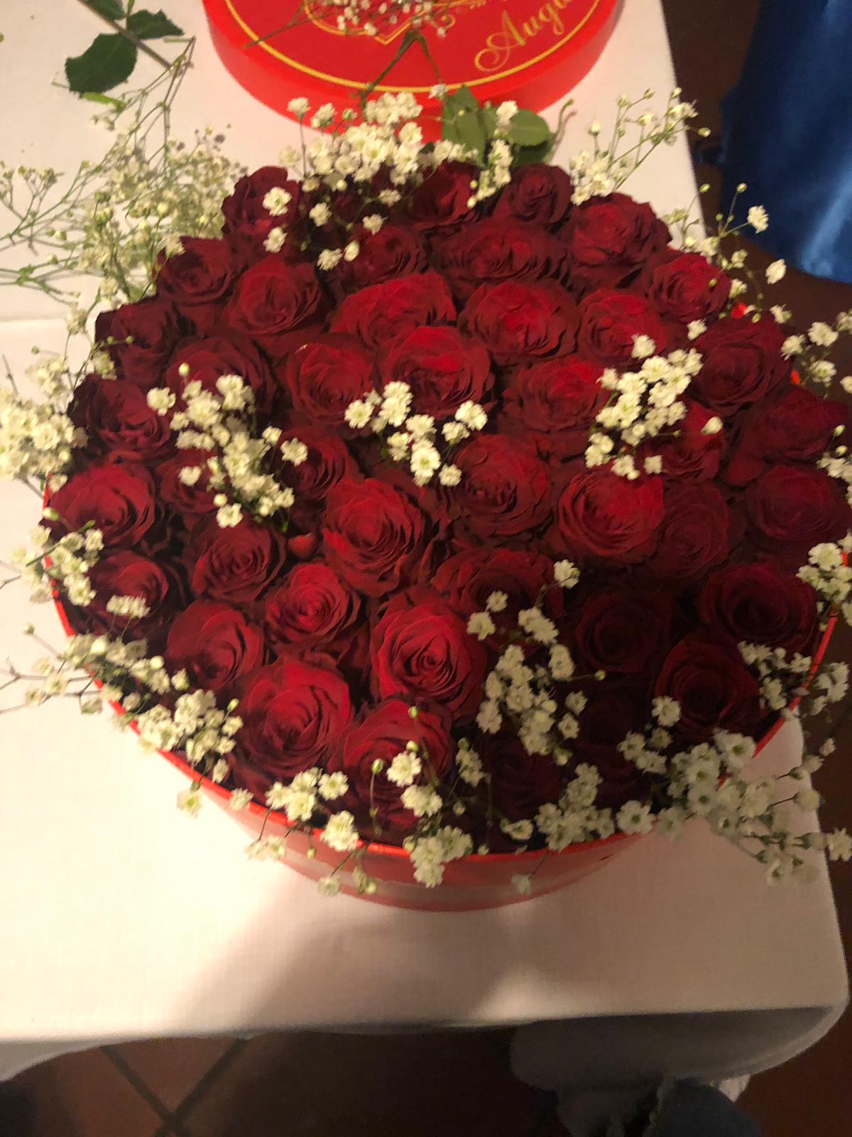 Una scatola a forma di cuore piena di rose rosse e gypsophila