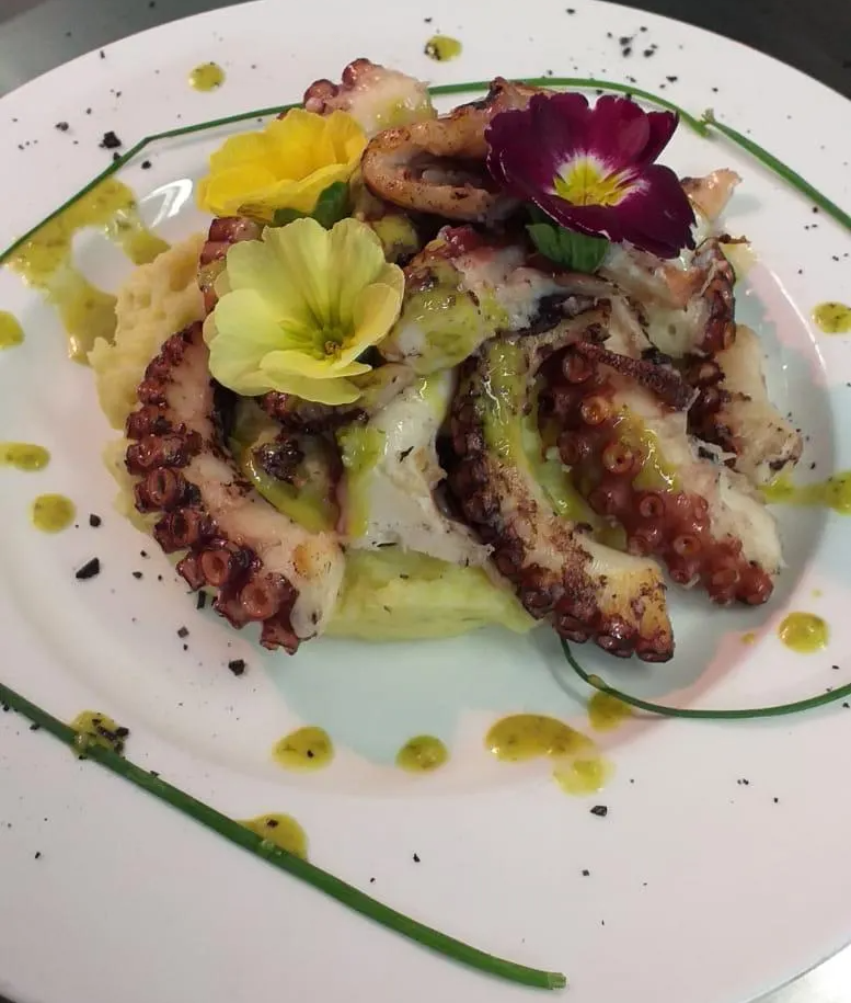 Un piatto di cibo con polpo e fiori sopra