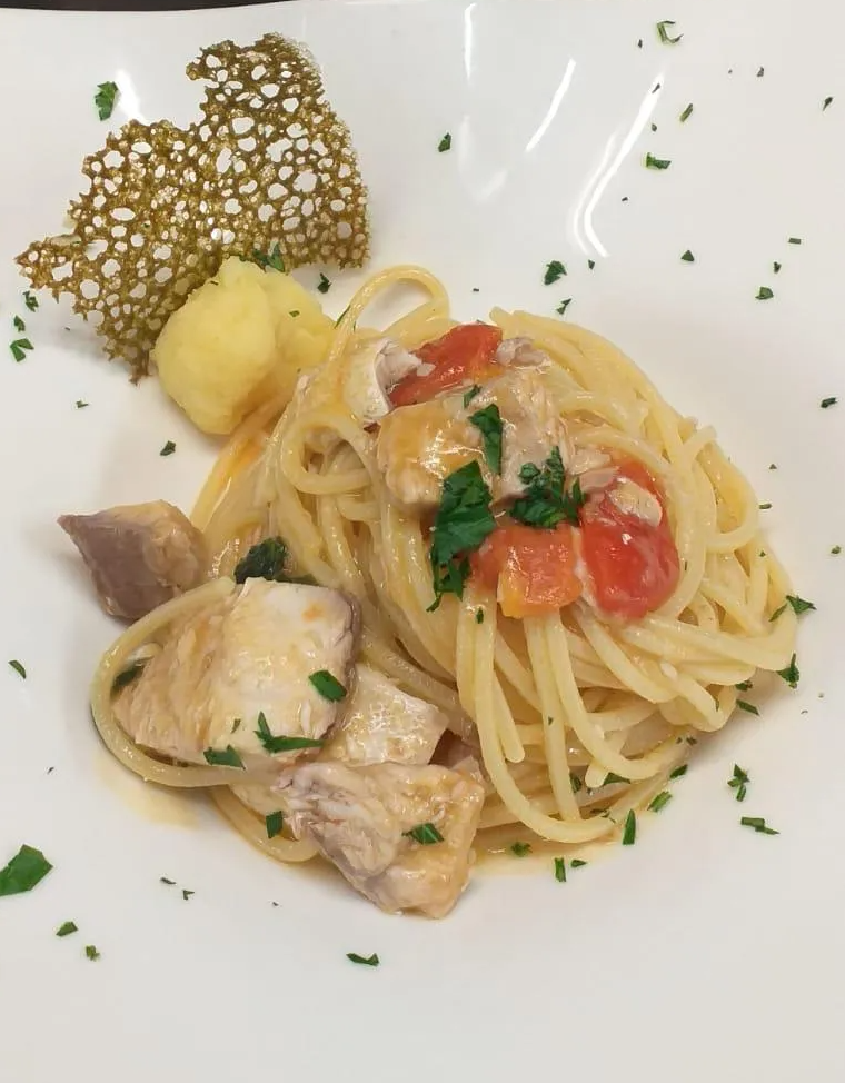 Un piatto di spaghetti con carne e pomodori sopra