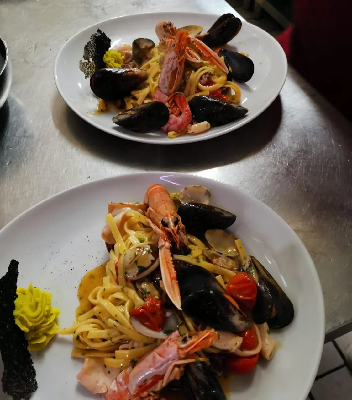Due piatti di frutti di mare e tagliatelle su un tavolo