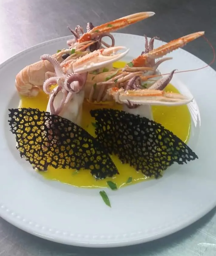 Un piatto bianco condito con frutti di mare e salsa