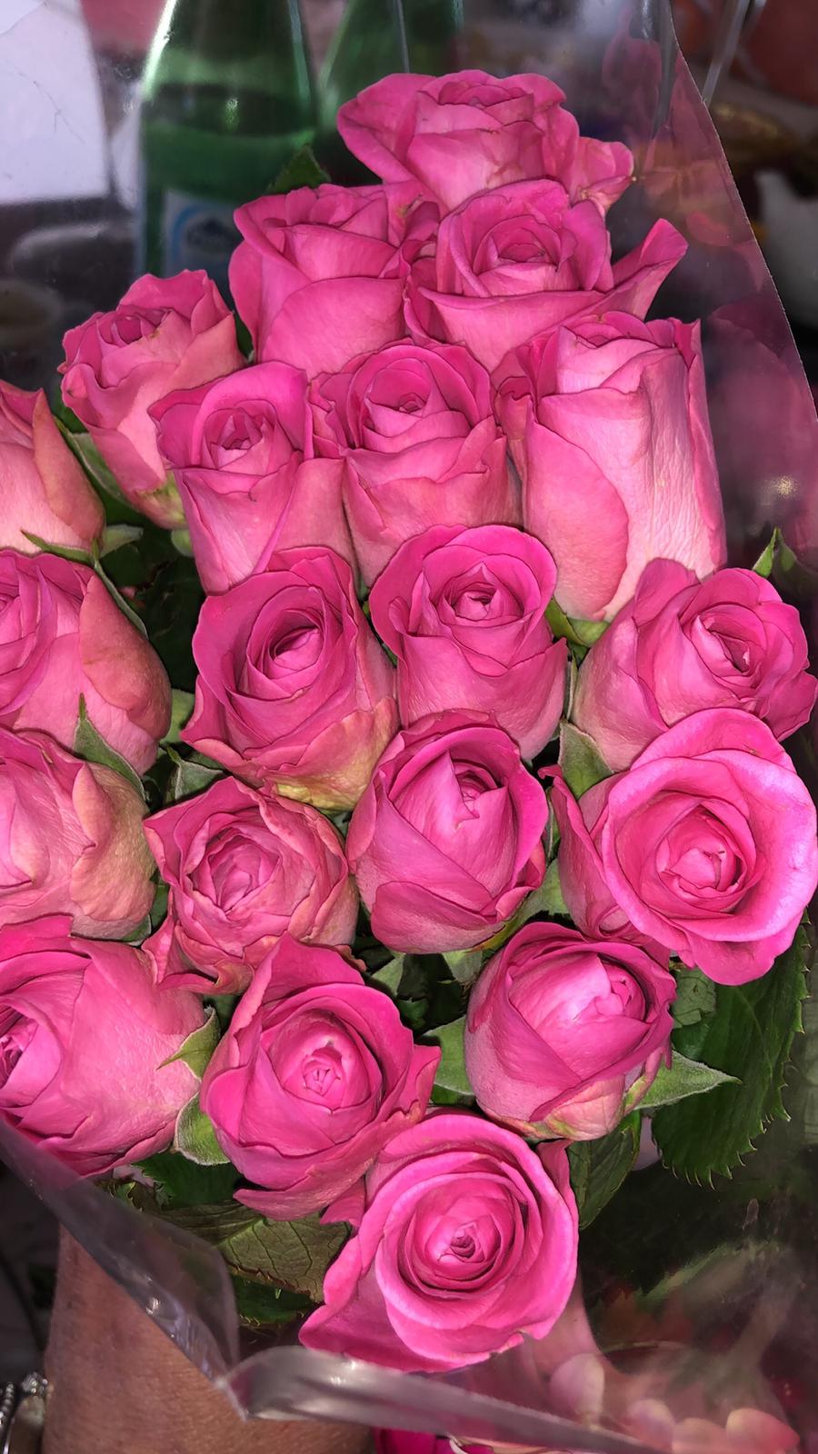 Un mazzo di rose rosa è appoggiato su un tavolo.