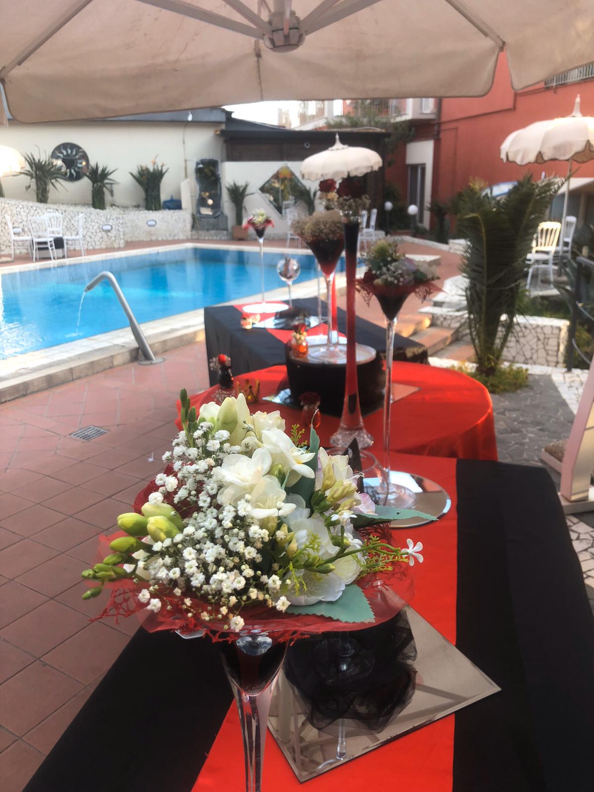 Un tavolo con bicchieri da martini e fiori davanti a una piscina