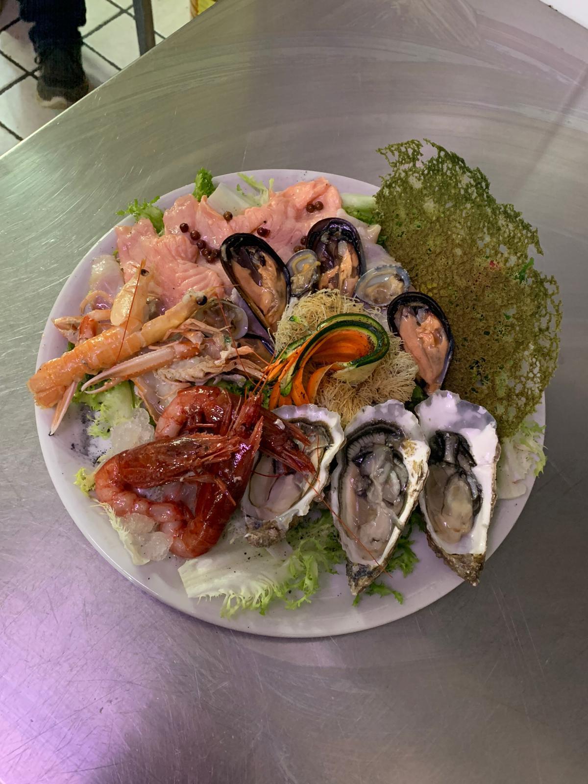 Un piatto di frutti di mare è appoggiato su un tavolo di acciaio inossidabile.