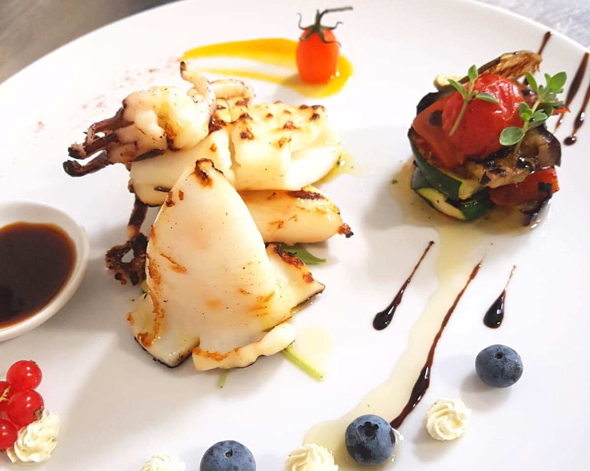 Un piatto di cibo con mirtilli e pomodori sopra