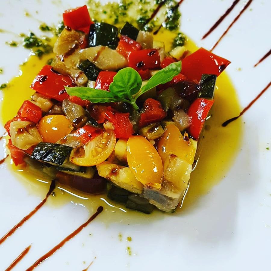 Un piatto bianco condito con una varietà di verdure e salsa