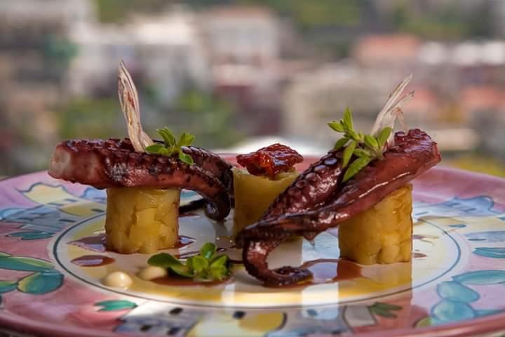 Un piatto di cibo con polpo e patate su un tavolo.
