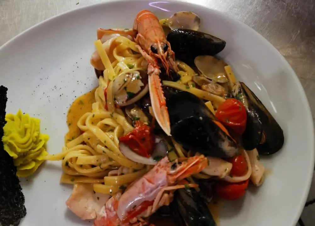 Un piatto bianco con sopra noodles e frutti di mare su un tavolo
