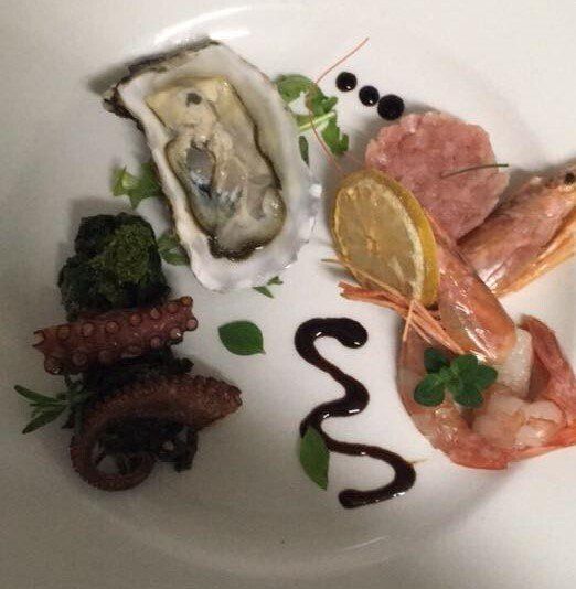 Un piatto bianco con ostriche, polpo e gamberi