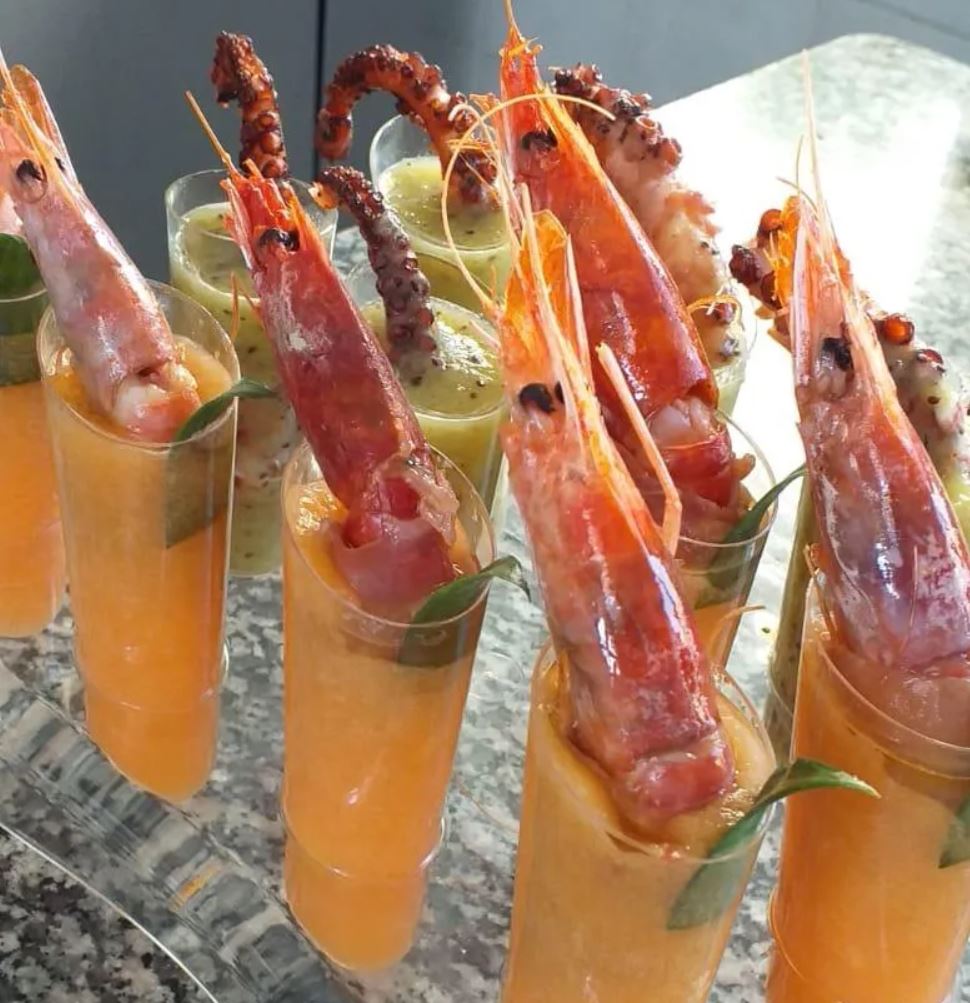 Una fila di bicchieri pieni di gamberi e polpo