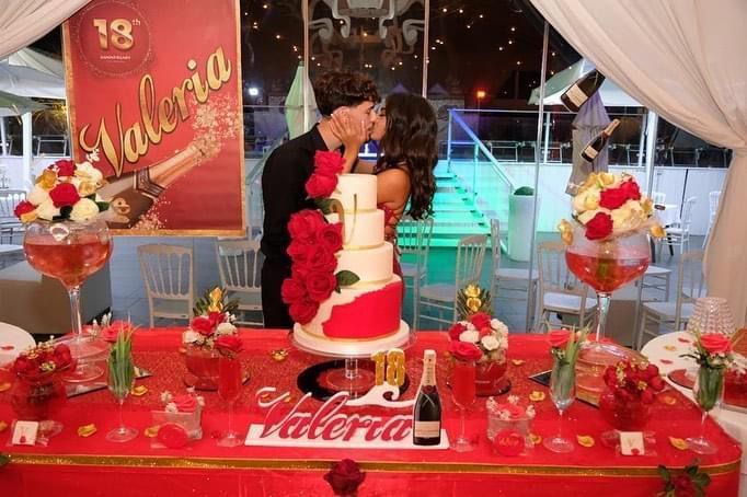 Un uomo e una donna che si baciano davanti a una torta con la scritta valeria